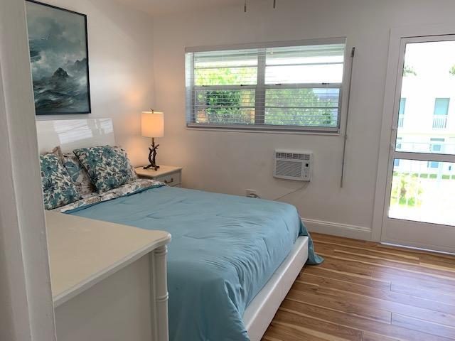 bedroom featuring a wall unit AC and wood-type flooring