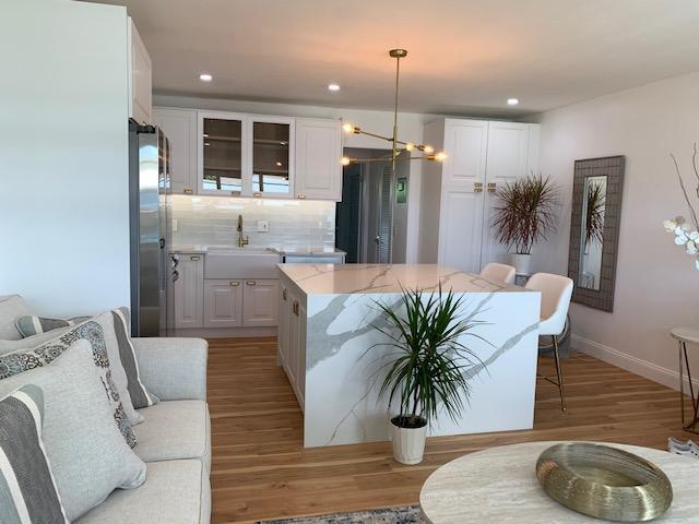 kitchen with white cabinets, decorative backsplash, hanging light fixtures, and sink