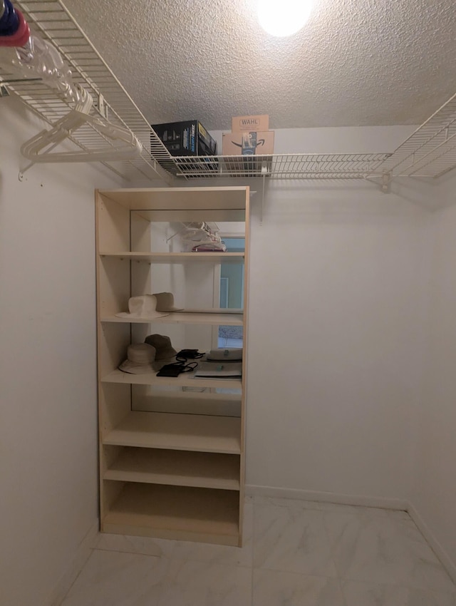 walk in closet featuring marble finish floor