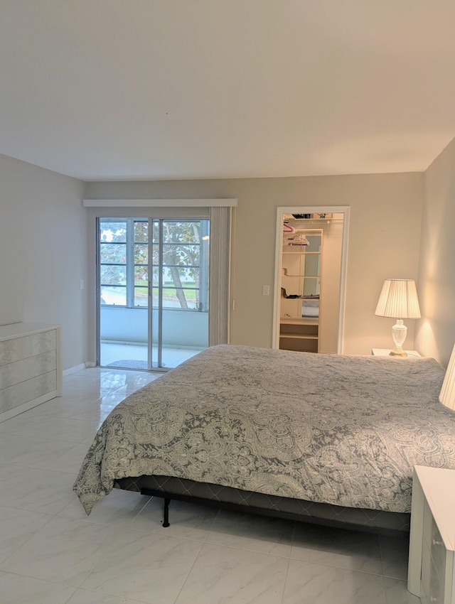 bedroom with a walk in closet, marble finish floor, and access to outside