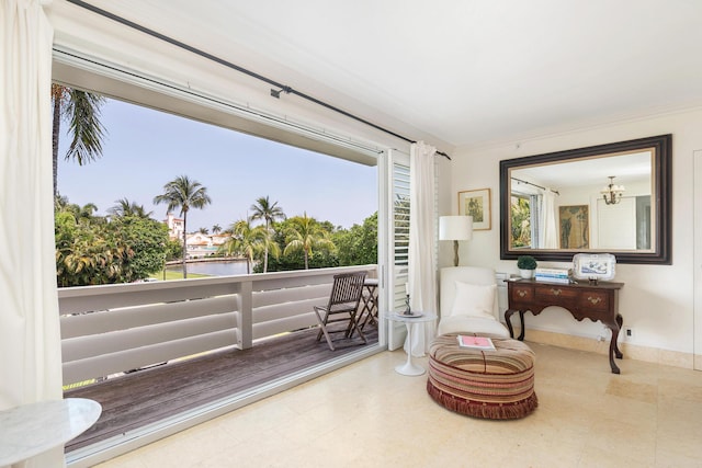 sitting room featuring a water view, crown molding, and an inviting chandelier