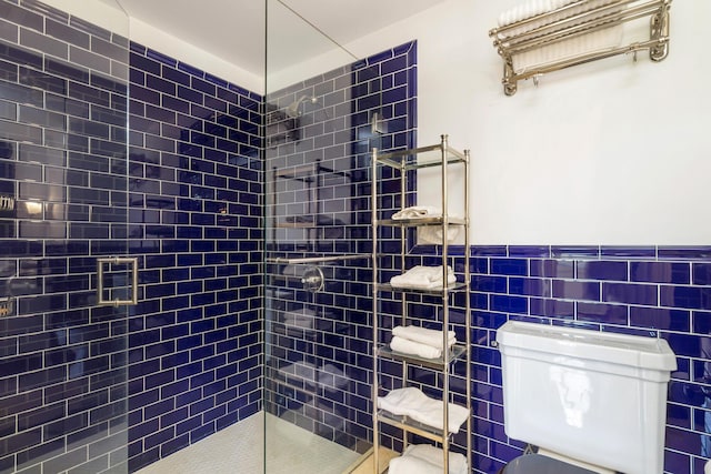 bathroom with toilet, tile walls, and a shower with shower door