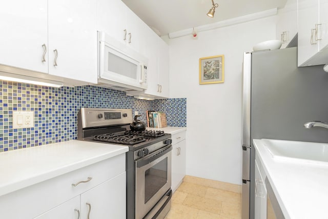 kitchen featuring stainless steel gas stove, sink, white cabinetry, and backsplash