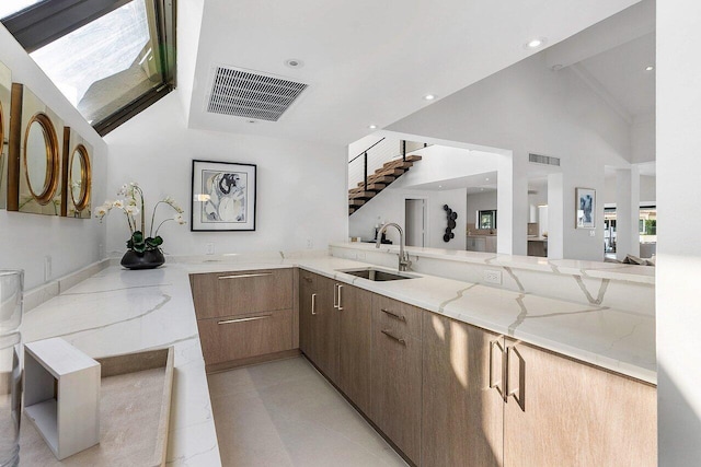 bathroom featuring high vaulted ceiling, sink, light stone countertops, and light tile flooring