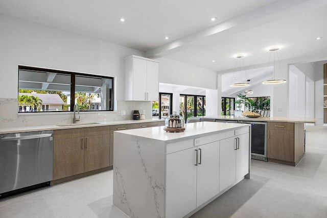 kitchen featuring a center island, hanging light fixtures, stainless steel dishwasher, white cabinets, and backsplash