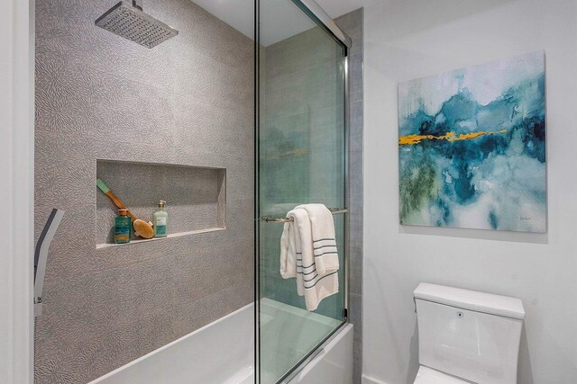 bathroom featuring bath / shower combo with glass door and toilet