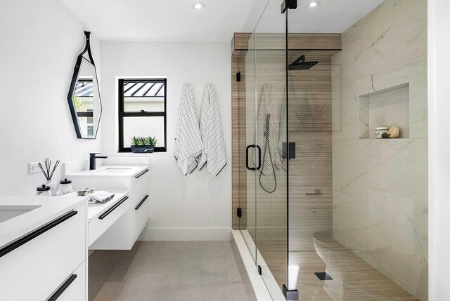 bathroom with a shower with door, dual bowl vanity, and tile floors