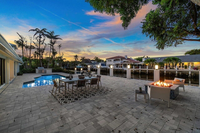 pool at dusk featuring a patio area and an outdoor fire pit