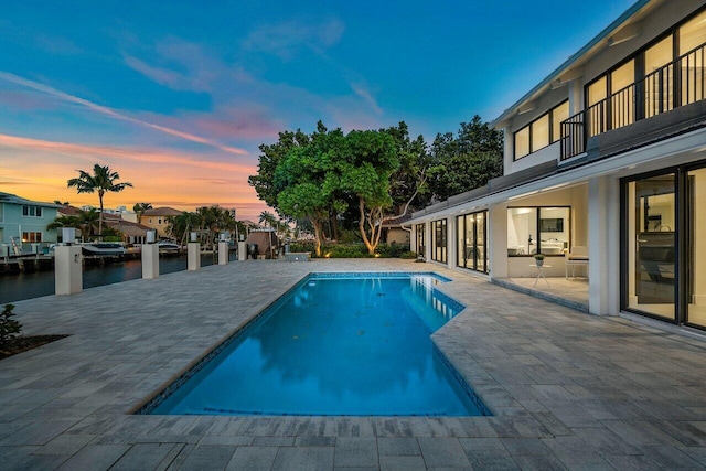 pool at dusk featuring a patio