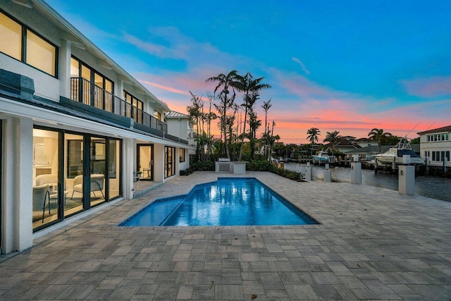 pool at dusk featuring a patio area