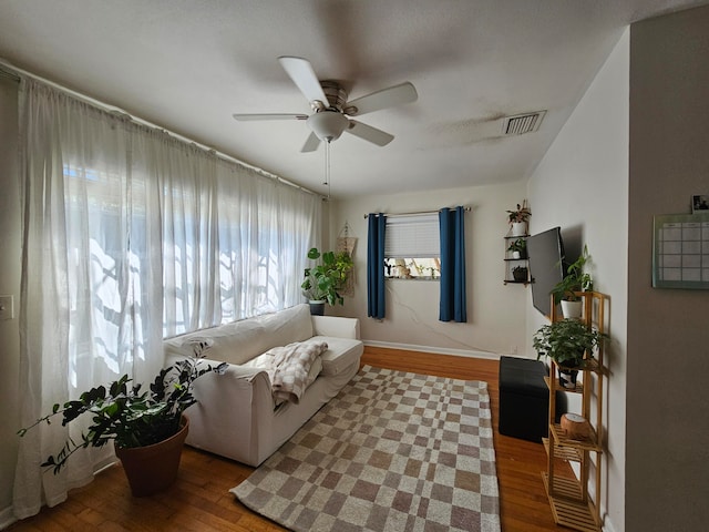 living room featuring dark wood-type flooring and ceiling fan