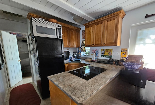 kitchen with beam ceiling, kitchen peninsula, a wealth of natural light, and black appliances