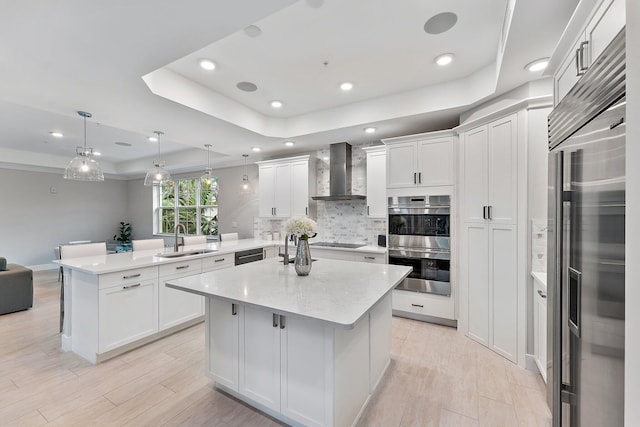 kitchen featuring sink, wall chimney range hood, kitchen peninsula, decorative light fixtures, and black appliances