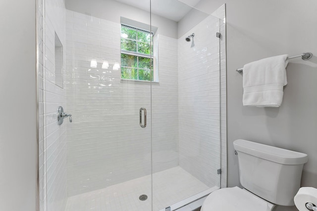 bathroom featuring toilet and a shower with shower door