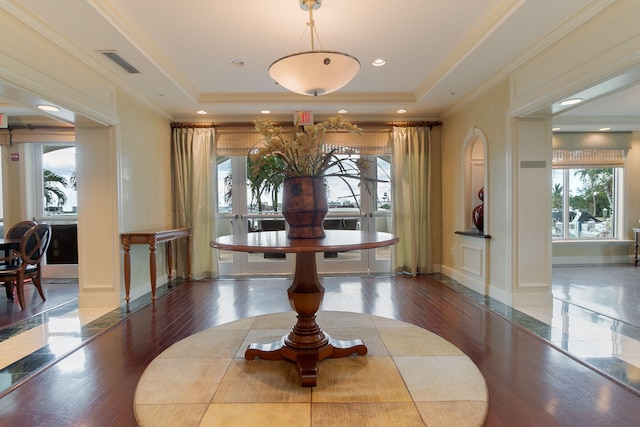 interior space with wood-type flooring, a raised ceiling, and crown molding