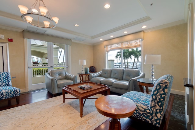 living room featuring an inviting chandelier, dark hardwood / wood-style flooring, a raised ceiling, and crown molding