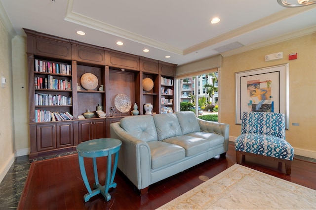 living room featuring dark hardwood / wood-style floors, ornamental molding, and a tray ceiling