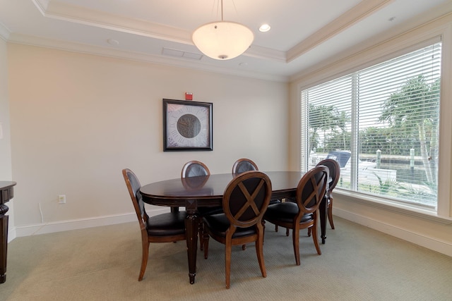 carpeted dining room with a healthy amount of sunlight, crown molding, and a raised ceiling