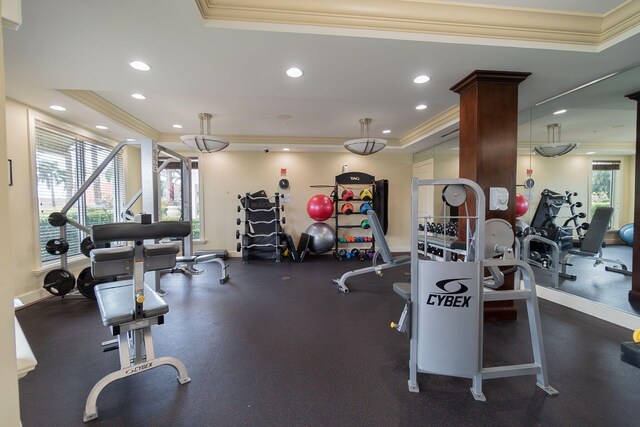 workout area featuring a tray ceiling, crown molding, and decorative columns