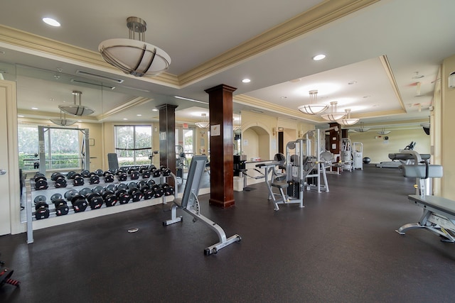 exercise room featuring decorative columns, a tray ceiling, and crown molding