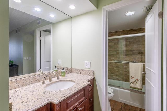 full bathroom featuring hardwood / wood-style floors, vanity, bath / shower combo with glass door, and toilet