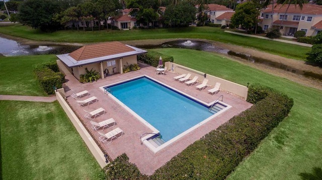 view of pool featuring an outbuilding, a yard, a water view, and a patio