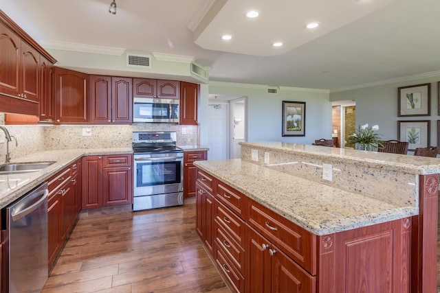 kitchen with light stone counters, a breakfast bar, stainless steel appliances, sink, and dark hardwood / wood-style floors