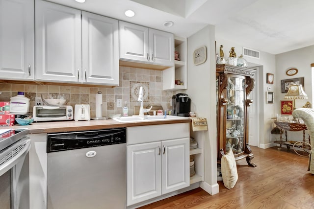 kitchen featuring white cabinetry, sink, stainless steel dishwasher, and light hardwood / wood-style flooring