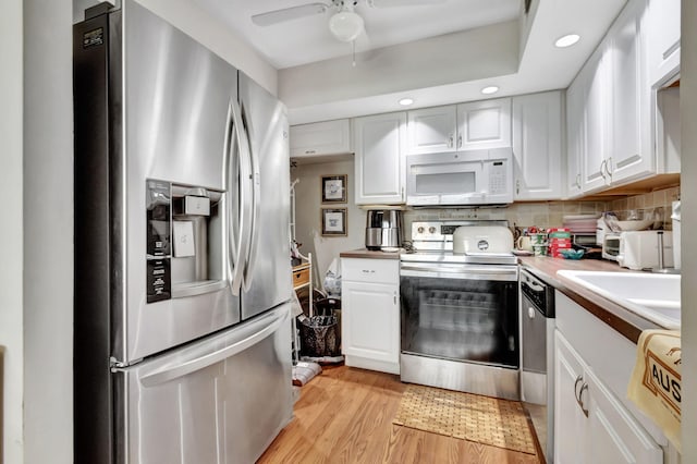 kitchen featuring ceiling fan, decorative backsplash, appliances with stainless steel finishes, light hardwood / wood-style floors, and white cabinetry