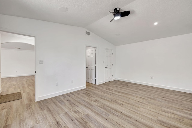 empty room featuring a textured ceiling, light hardwood / wood-style flooring, ceiling fan, and lofted ceiling