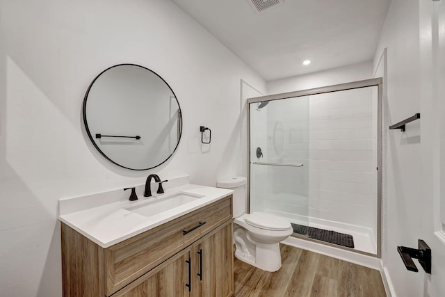 bathroom with wood-type flooring, vanity, toilet, and walk in shower