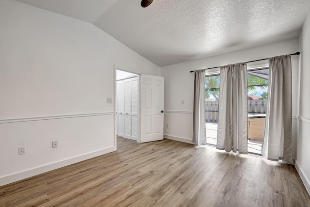 spare room featuring ceiling fan, light hardwood / wood-style floors, a textured ceiling, and vaulted ceiling