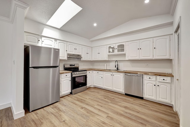 kitchen featuring white cabinetry, sink, light hardwood / wood-style flooring, lofted ceiling with skylight, and appliances with stainless steel finishes