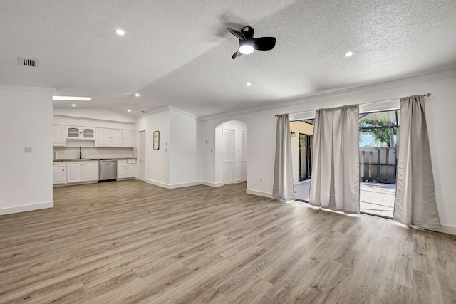 unfurnished living room featuring vaulted ceiling, light wood-type flooring, a textured ceiling, and ornamental molding