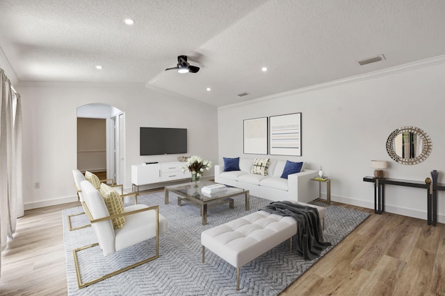 living room with lofted ceiling, crown molding, ceiling fan, a textured ceiling, and light hardwood / wood-style floors