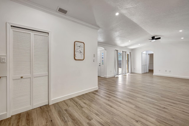 unfurnished living room with lofted ceiling, a textured ceiling, light hardwood / wood-style flooring, and crown molding