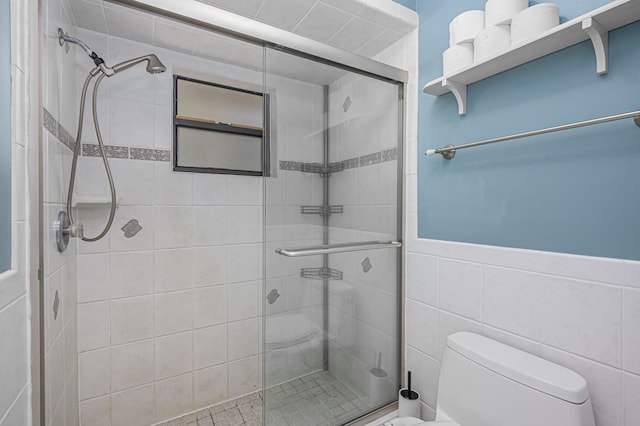 bathroom featuring a shower with door, toilet, and tile walls