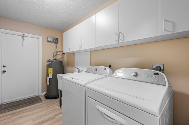 laundry room with cabinets, electric water heater, a textured ceiling, washing machine and dryer, and light hardwood / wood-style floors