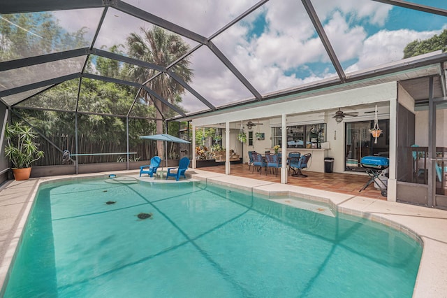 view of pool with a patio area, ceiling fan, and glass enclosure