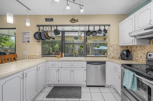 kitchen with decorative backsplash, appliances with stainless steel finishes, white cabinets, and light tile patterned floors