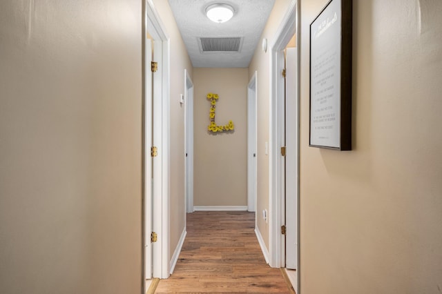 corridor featuring a textured ceiling and light wood-type flooring