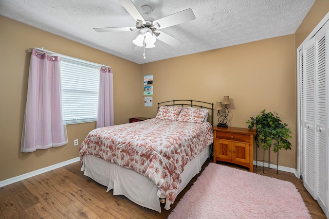 bedroom featuring a closet, a textured ceiling, wood-type flooring, and ceiling fan