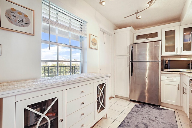 kitchen with stainless steel appliances, light stone counters, and light tile patterned flooring