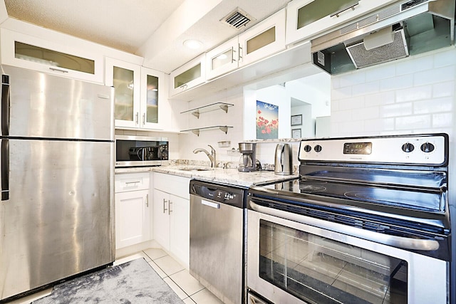 kitchen featuring exhaust hood, light stone countertops, white cabinets, and stainless steel appliances