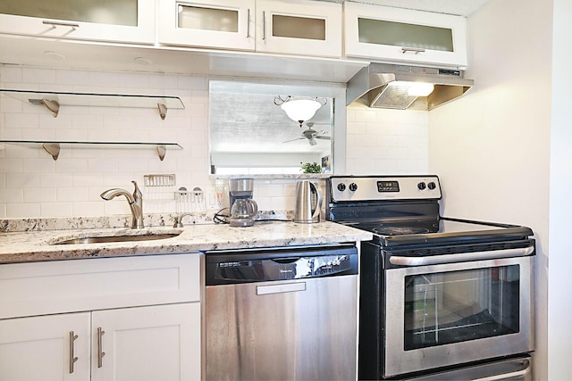 kitchen featuring appliances with stainless steel finishes, light stone counters, extractor fan, sink, and white cabinets