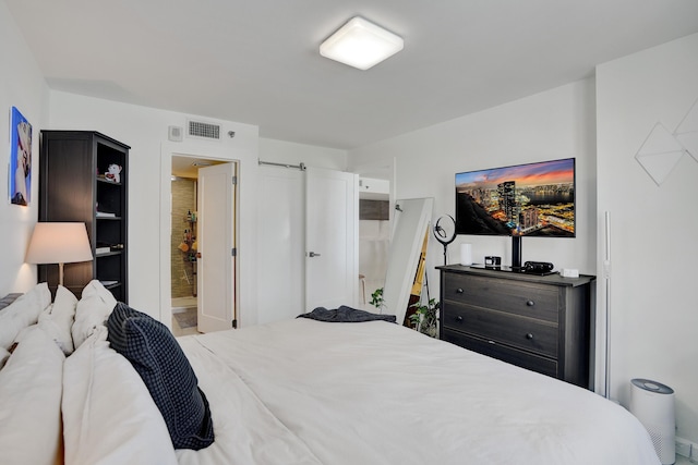 bedroom featuring ensuite bath and a barn door