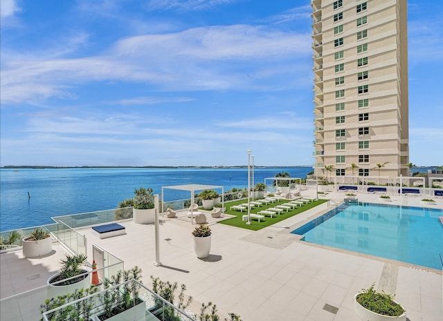 view of swimming pool featuring a patio and a water view