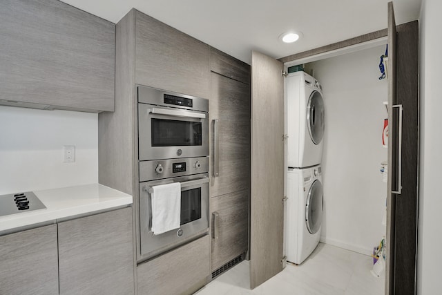 kitchen featuring double oven, stacked washer and clothes dryer, black electric stovetop, and light tile patterned flooring