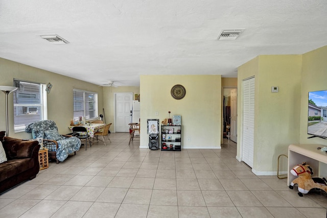 tiled living room with ceiling fan and a textured ceiling