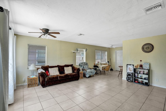 living room with ceiling fan, light tile patterned floors, and a textured ceiling